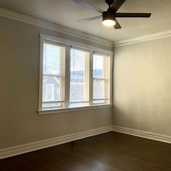 a room with a ceiling fan and a window with blinds.