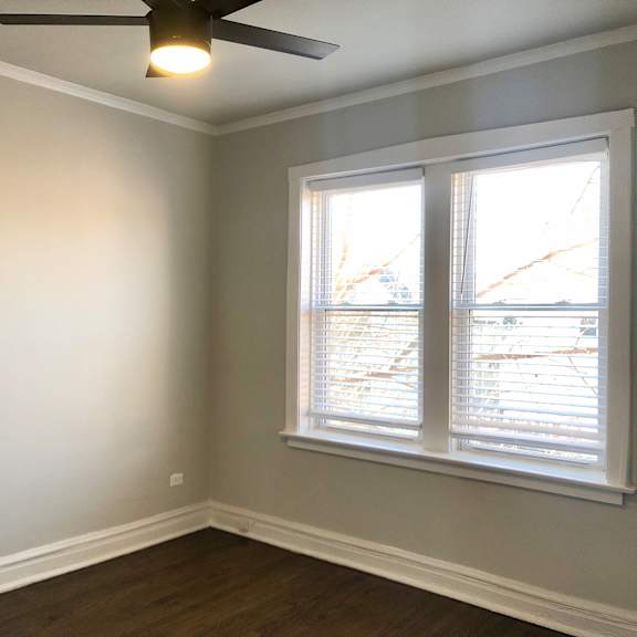 a room with a ceiling fan and a window with blinds.