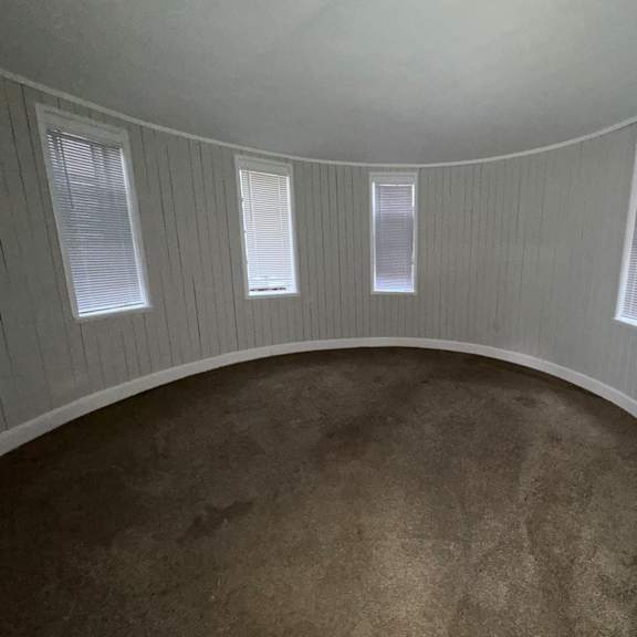 a round room with three windows and a carpeted floor.