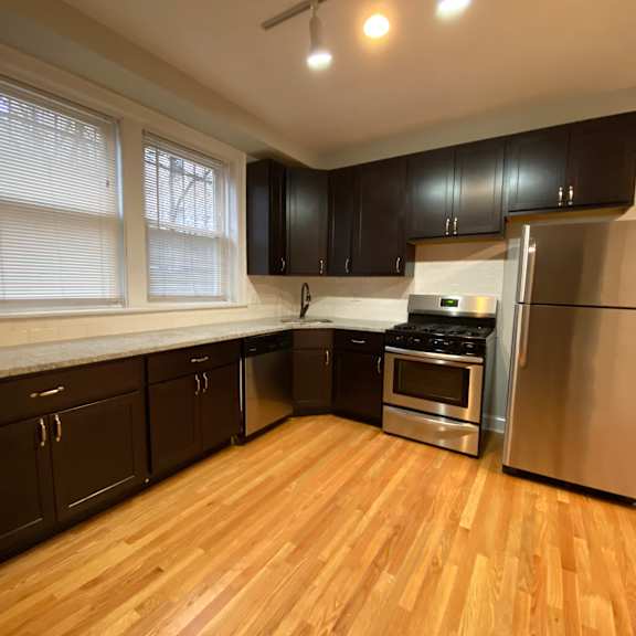 a kitchen with wooden floors and black cabinets.