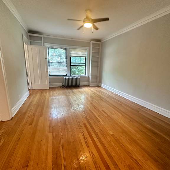 an empty living room with wood floors and a ceiling fan