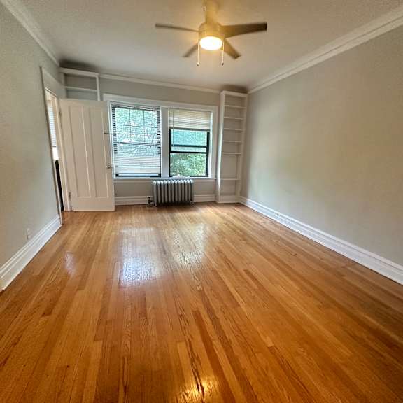 an empty living room with wood floors and a ceiling fan