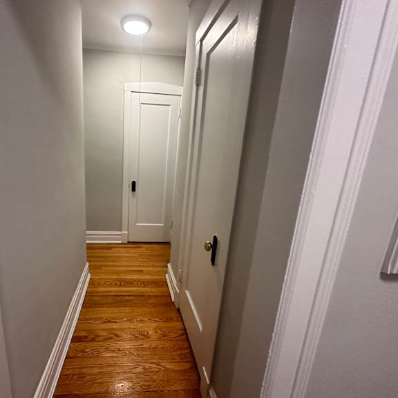 a small hallway with a white door and wood floors