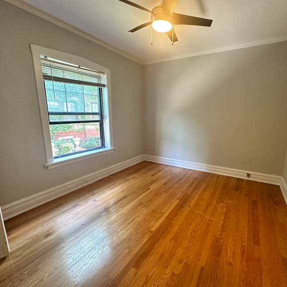 an empty bedroom with hardwood floors and a ceiling fan