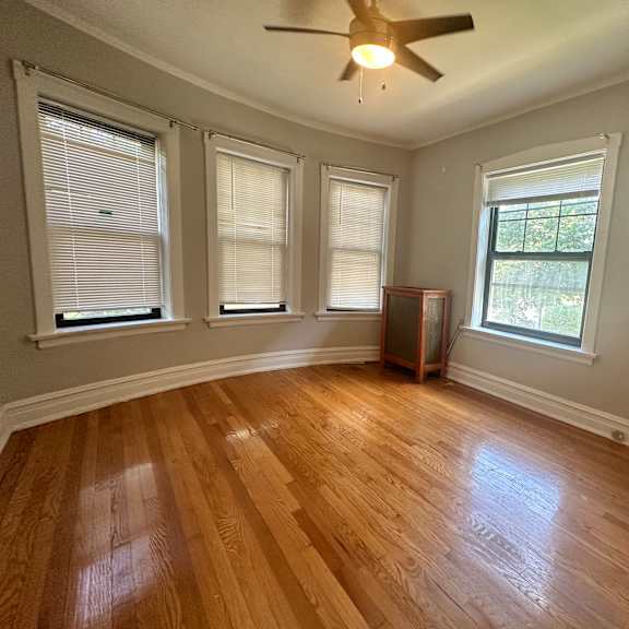 an empty living room with wood floors and a ceiling fan