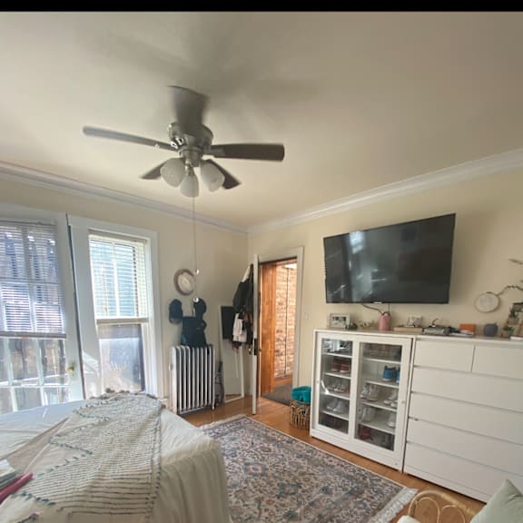 a bedroom with a bed and a ceiling fan and a tv