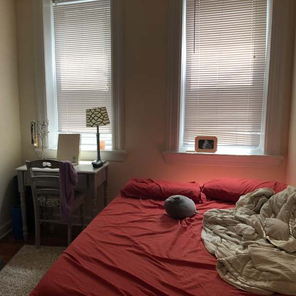 a bedroom with a red bedspread and a grey blanket.