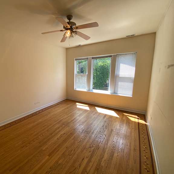 a room with a ceiling fan and wooden flooring.
