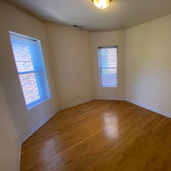 a room with wooden floors and two windows.