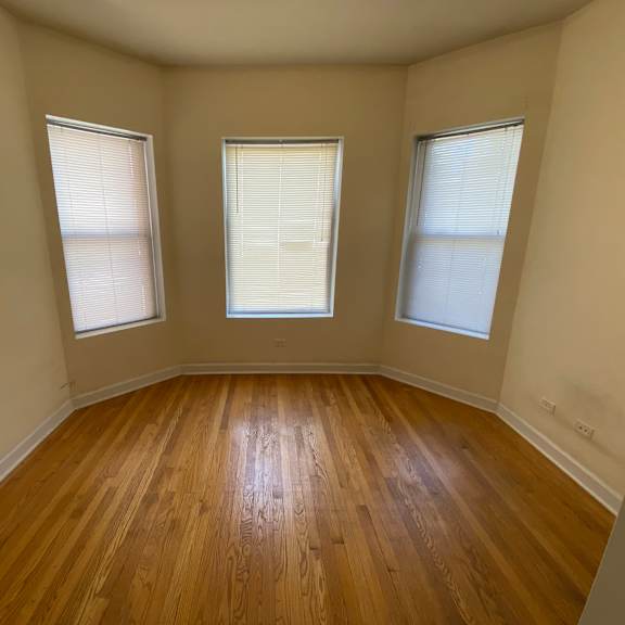 a room with wooden floors and two windows.