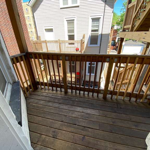 a wooden deck with a railing and a building in the background.