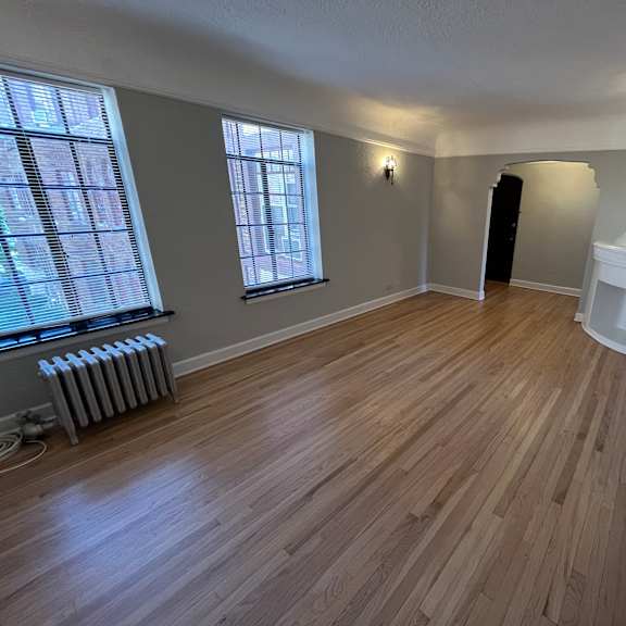a room with wooden flooring and a window with blinds.