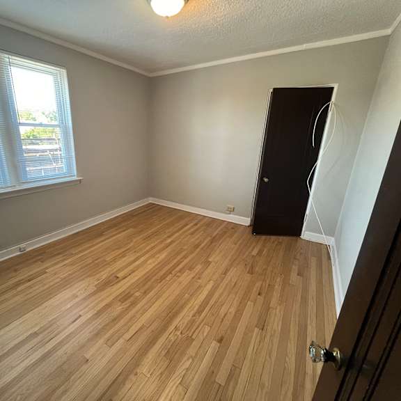 a room with wooden flooring and a window with blinds.