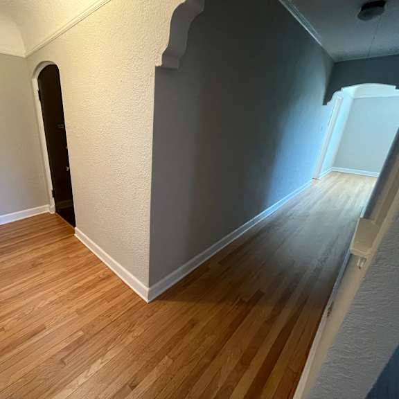 a hallway with wood flooring and white walls.