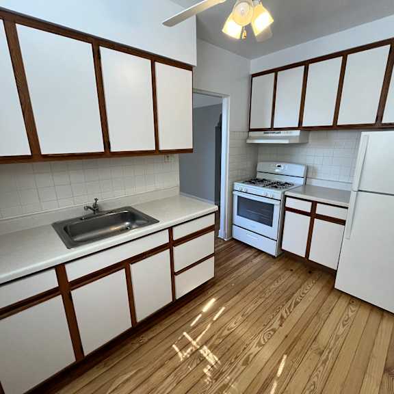 a kitchen with white cabinets and a wooden floor.