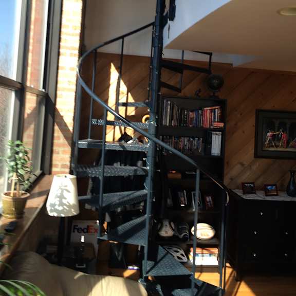 a spiral staircase in a home with a black metal railing.