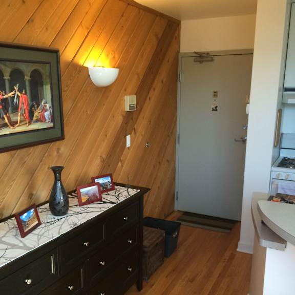 a room with a wooden ceiling and a black dresser with a vase on top.