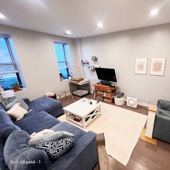 a living room with a blue couch, a white coffee table, and a tv on a wooden stand.