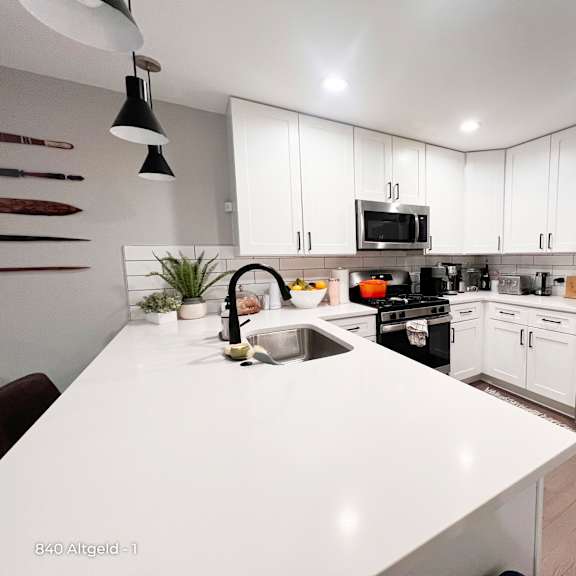 a modern kitchen with a white countertop and stainless steel appliances.