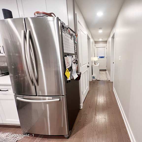 a stainless steel refrigerator is in a narrow hallway.