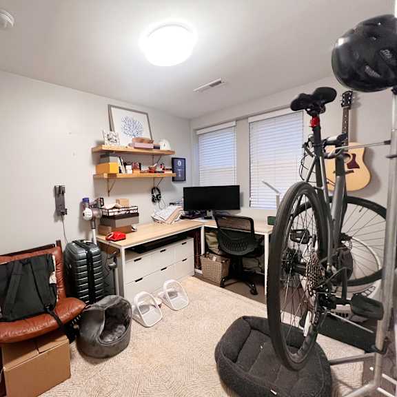 a room with a bicycle, a chair, and a desk.