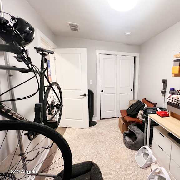 a room with a bicycle, a desk, and a chair.