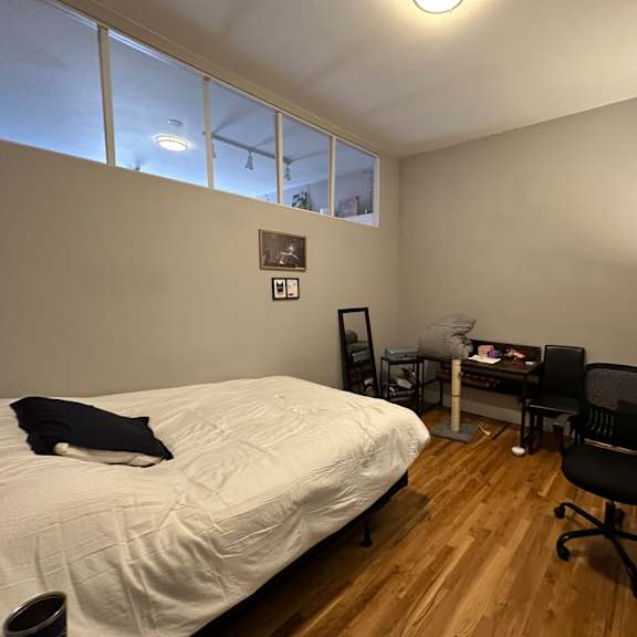 a bedroom with a bed, desk, chair, and a window.