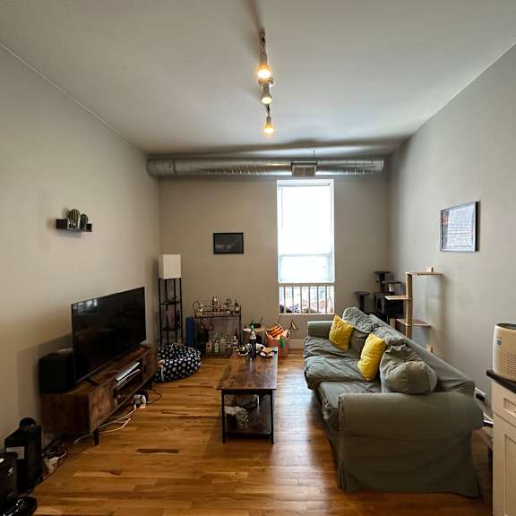 a living room with a grey couch and a wooden floor.