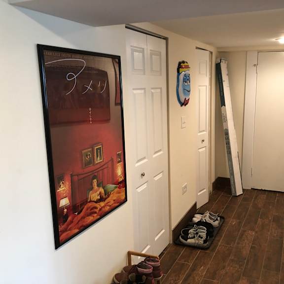 a hallway with a painting on the wall and a pair of shoes on the floor.