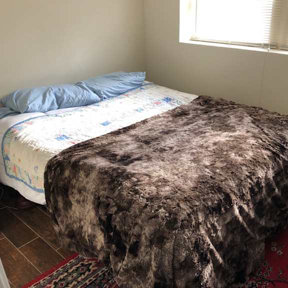 a bed with a blue pillow and a black box on the floor.