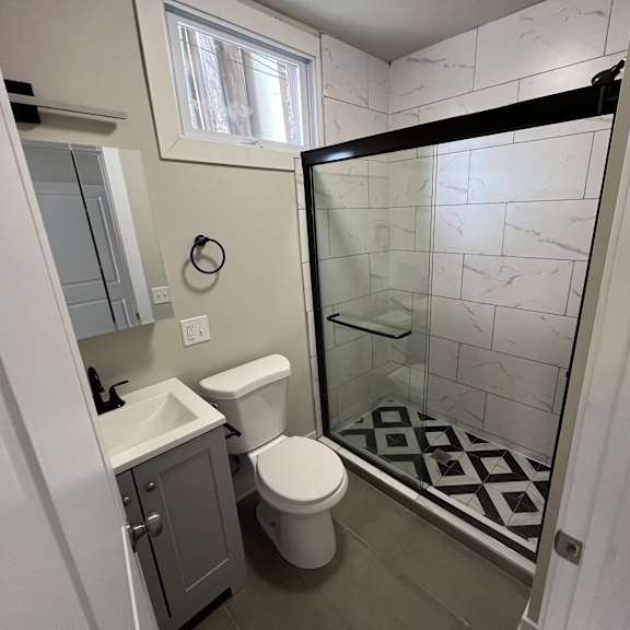 a white toilet is in a bathroom with a walk-in shower.