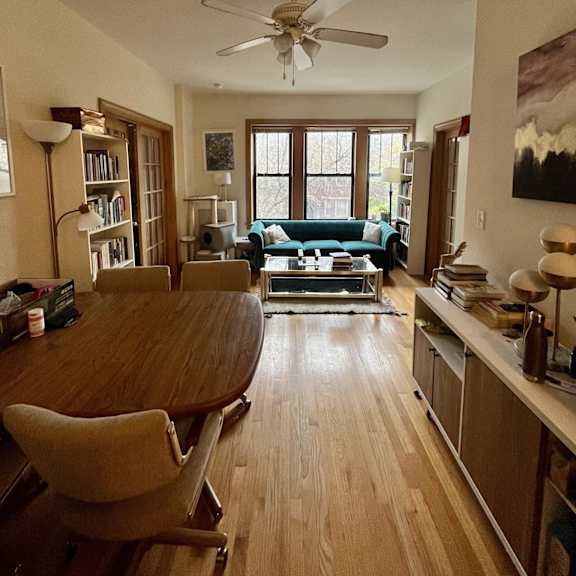 a living room with a table and a ceiling fan