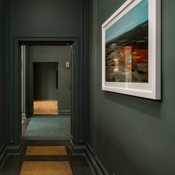 a hallway with green walls and a painting on the wall