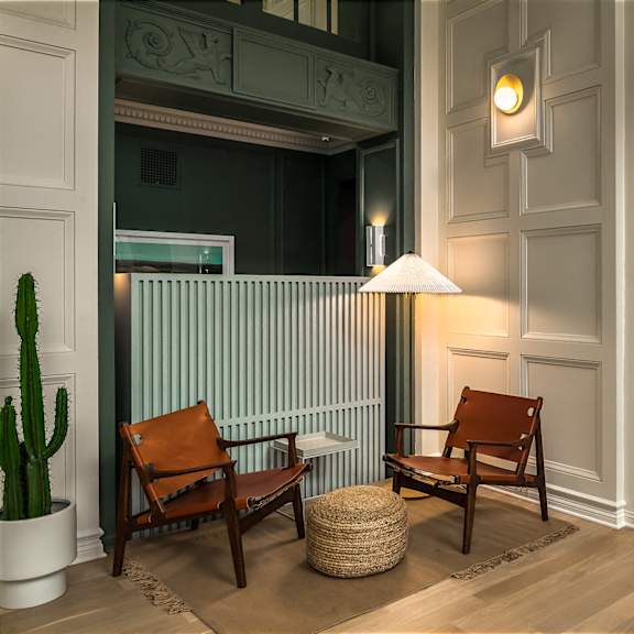 a lobby with two chairs and a lamp on the wall