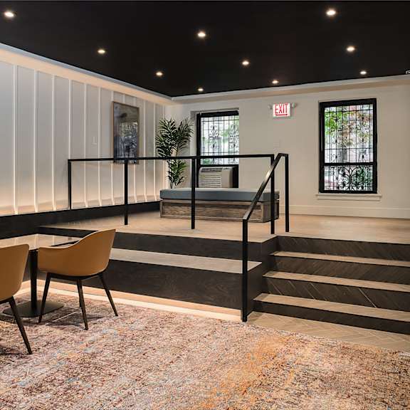 the lobby of a building with tables and chairs and a staircase