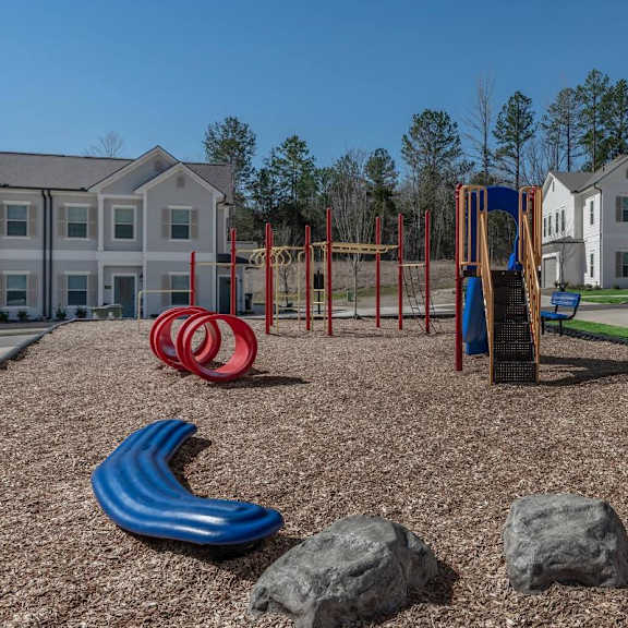 an empty playground with rocks and slides in front of apartment buildings