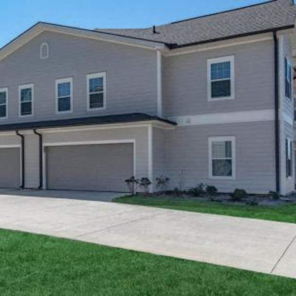 a house with two garage doors on a sidewalk