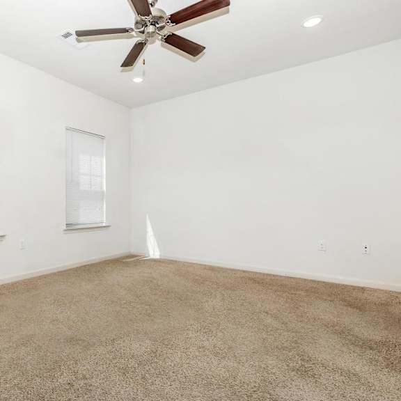 an empty living room with a ceiling fan and a window