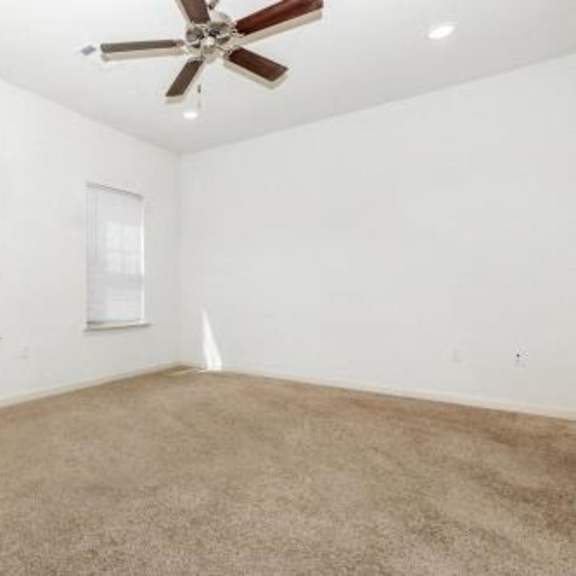 an empty room with a ceiling fan and two windows