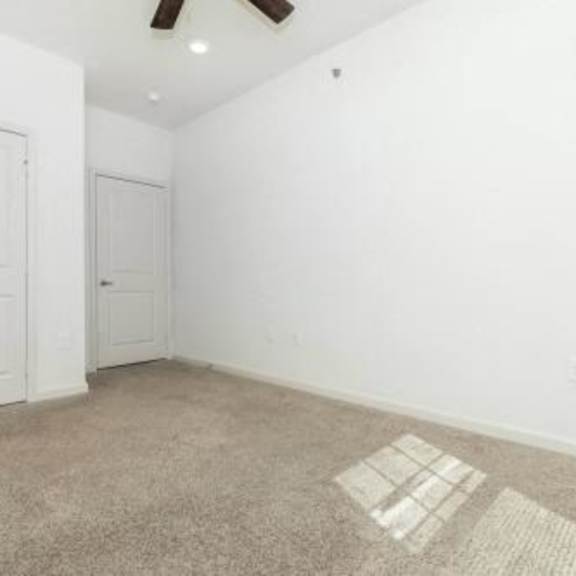 an empty room with a door and a ceiling fan