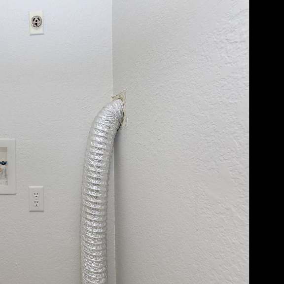a white wall with a socket and a white hose.