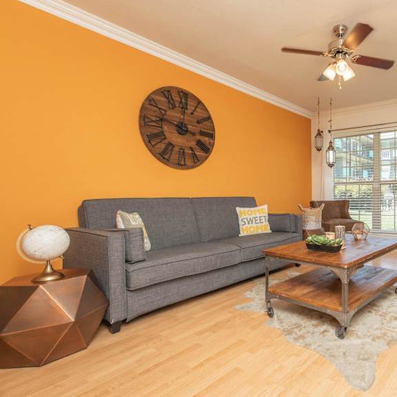 a living room with a grey couch, a wooden coffee table, and a ceiling fan. at the cove at state street apartments, louisiana, 70802