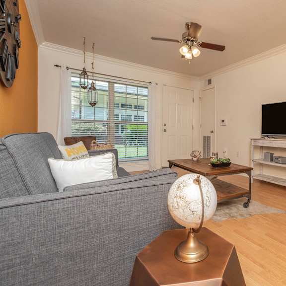 a living room with a grey couch, a wooden coffee table, and a television on a stand. at the cove at state street apartments, baton rouge, la
