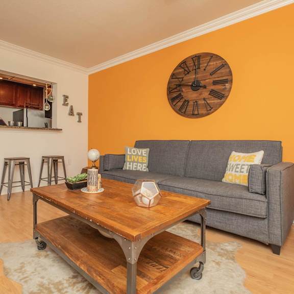 a living room with a grey couch and a wooden coffee table. at the cove at state street apartments, baton rouge