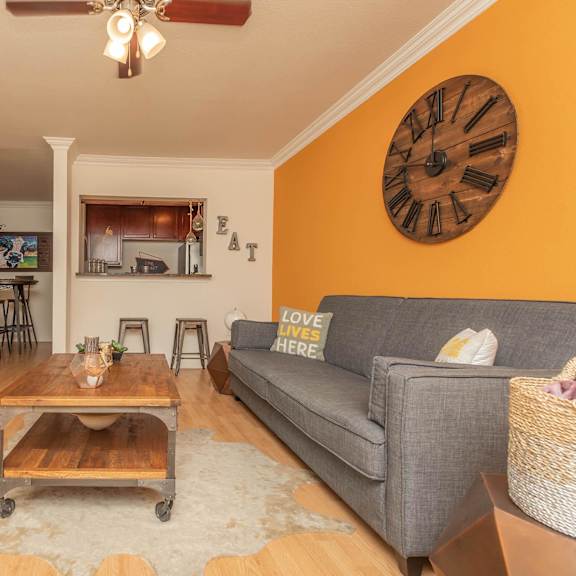 a living room with a grey couch, a wooden coffee table, and a flat screen tv. at the cove at state street apartments, baton rouge, la