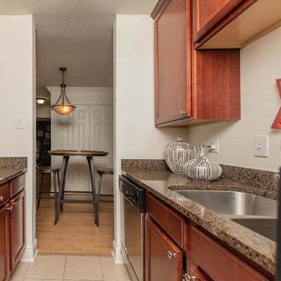 a kitchen with brown cabinets and a granite counter top. at the cove at state street apartments, baton rouge, la, 70802