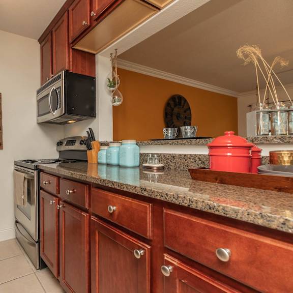 a kitchen with a black fridge, wooden cabinets, and a granite countertop. at the cove at state street apartments, baton rouge, louisiana