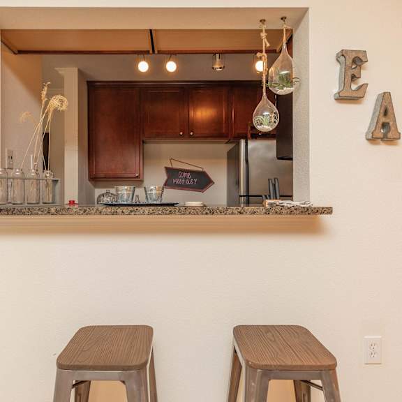 a kitchen with a counter and two stools. at the cove at state street apartments, baton rouge