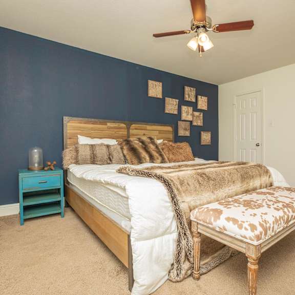 a bedroom with a bed, a bench, and a ceiling fan. at the cove at state street apartments, louisiana, 70802