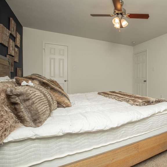 a bedroom with a bed, pillows, and a ceiling fan. at the cove at state street apartments, baton rouge, la